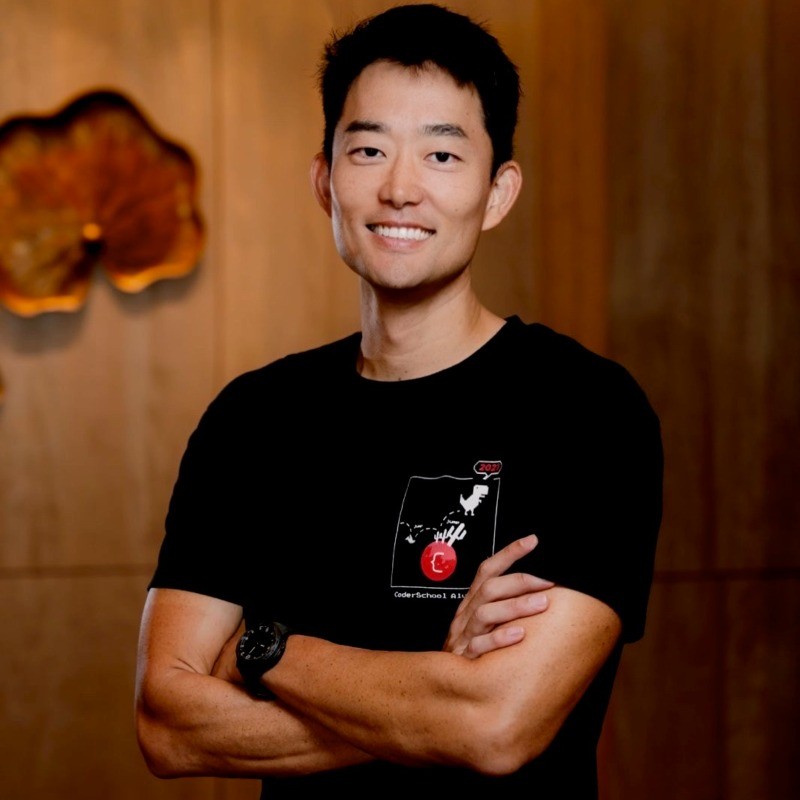 Charles Lee smiling, with folded arms, wearing a black CoderSchool T-shirt.